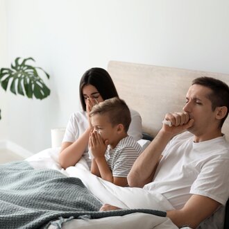 Vater, Mutter und Sohn liegen krank im Bett